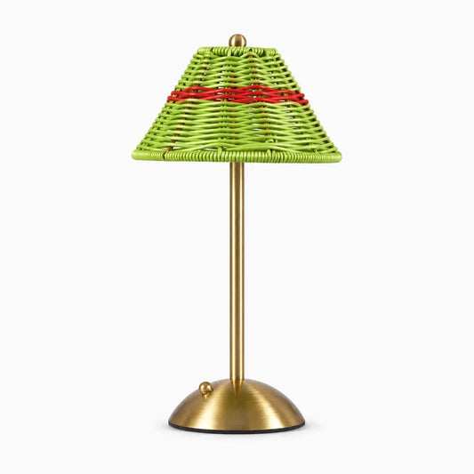 Lampe de bureau verte avec structure en rotin, diffusant une lumière chaude sur un plan de travail