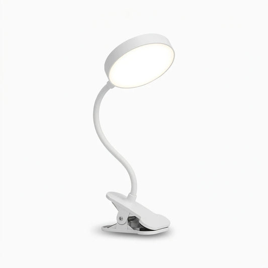 Lampe de chevet à pince noire fixée sur le bord d'une table de nuit, diffusant une lumière chaude