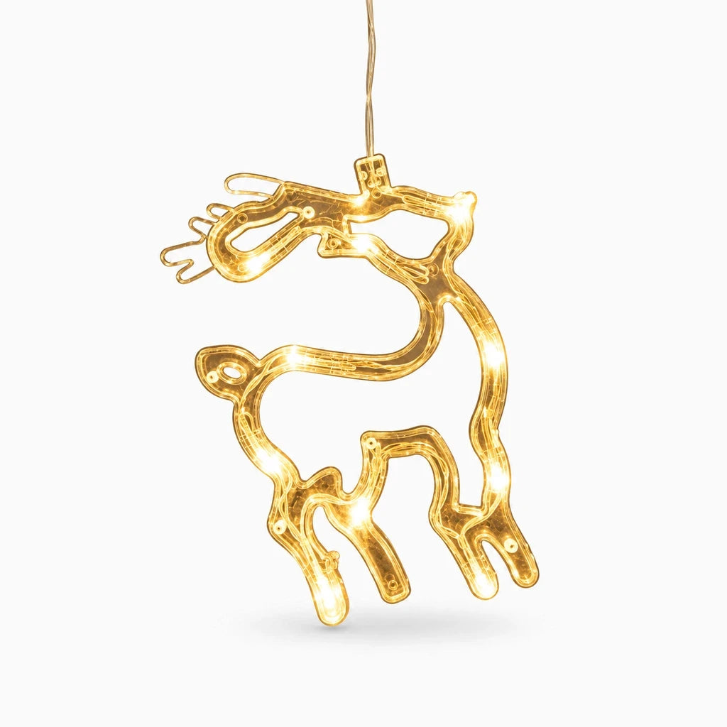 Lampe de noël installée sur un rebord de fenêtre illuminant la nuit avec motifs de renne et Père Noël