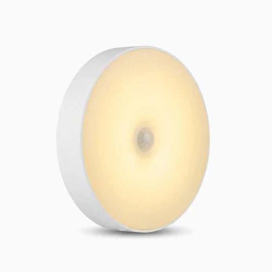Veilleuse avec détecteur de mouvement émettant une lumière blanche chaude sur une table de chevet